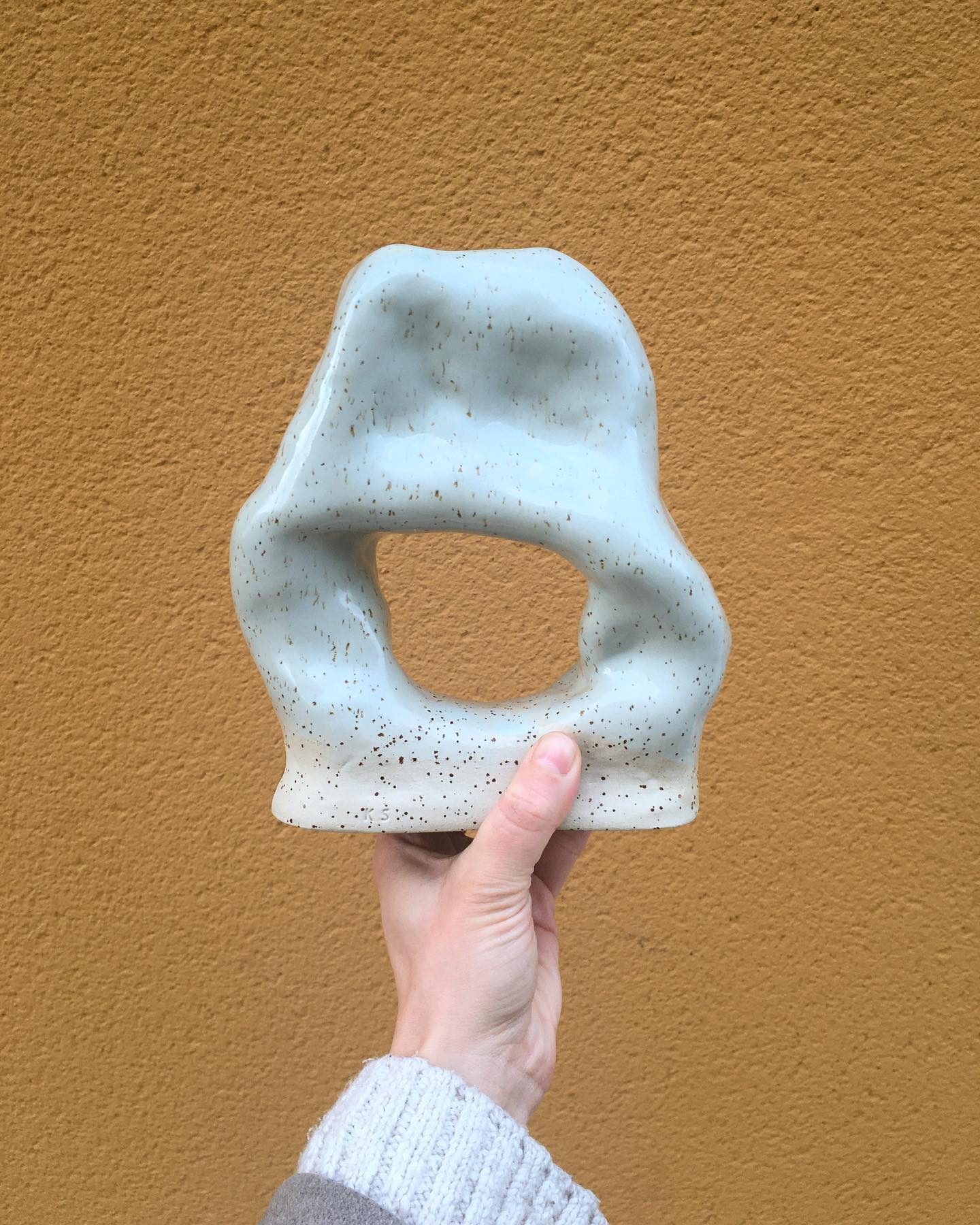 Handgjord keramisk skulptur mot orange vägg