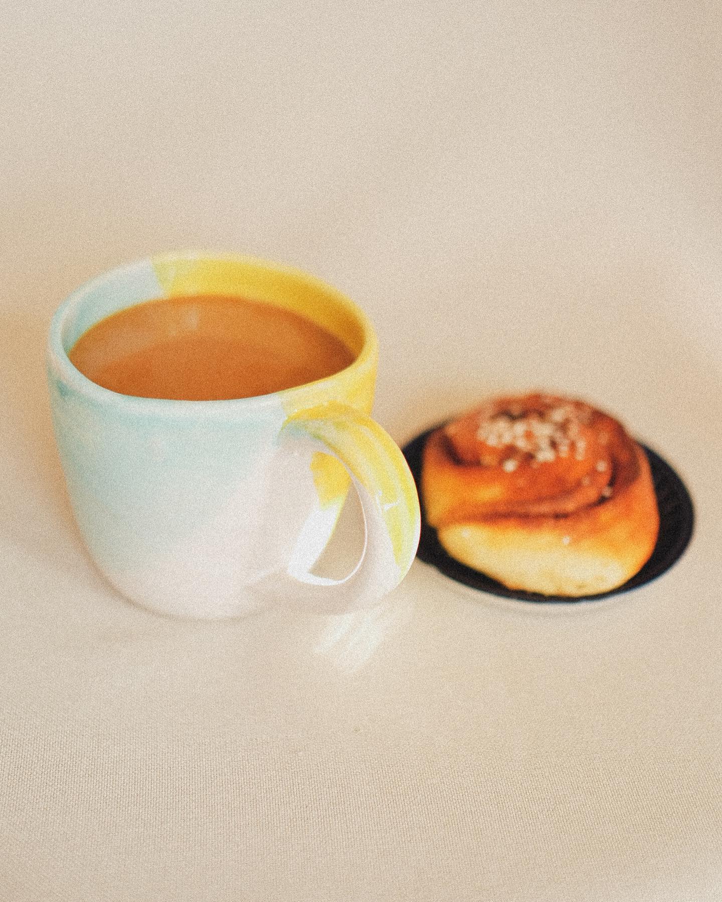Handgjord kopp med kaffe och kanelbulle